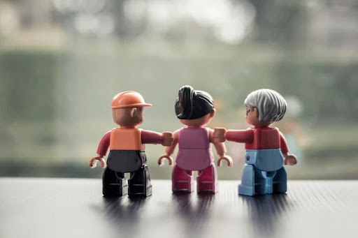Drie Lego-figuren van verschillende generaties, gearmd naast elkaar