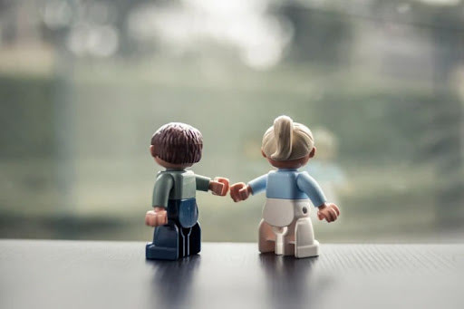 Twee Lego-poppetjes die van achteren gezien een vuistje geven