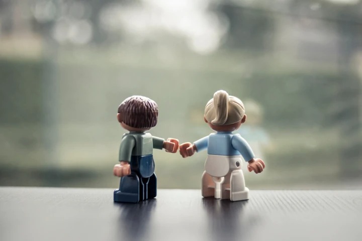 Twee Lego-poppetjes die van achteren gezien een vuistje geven
