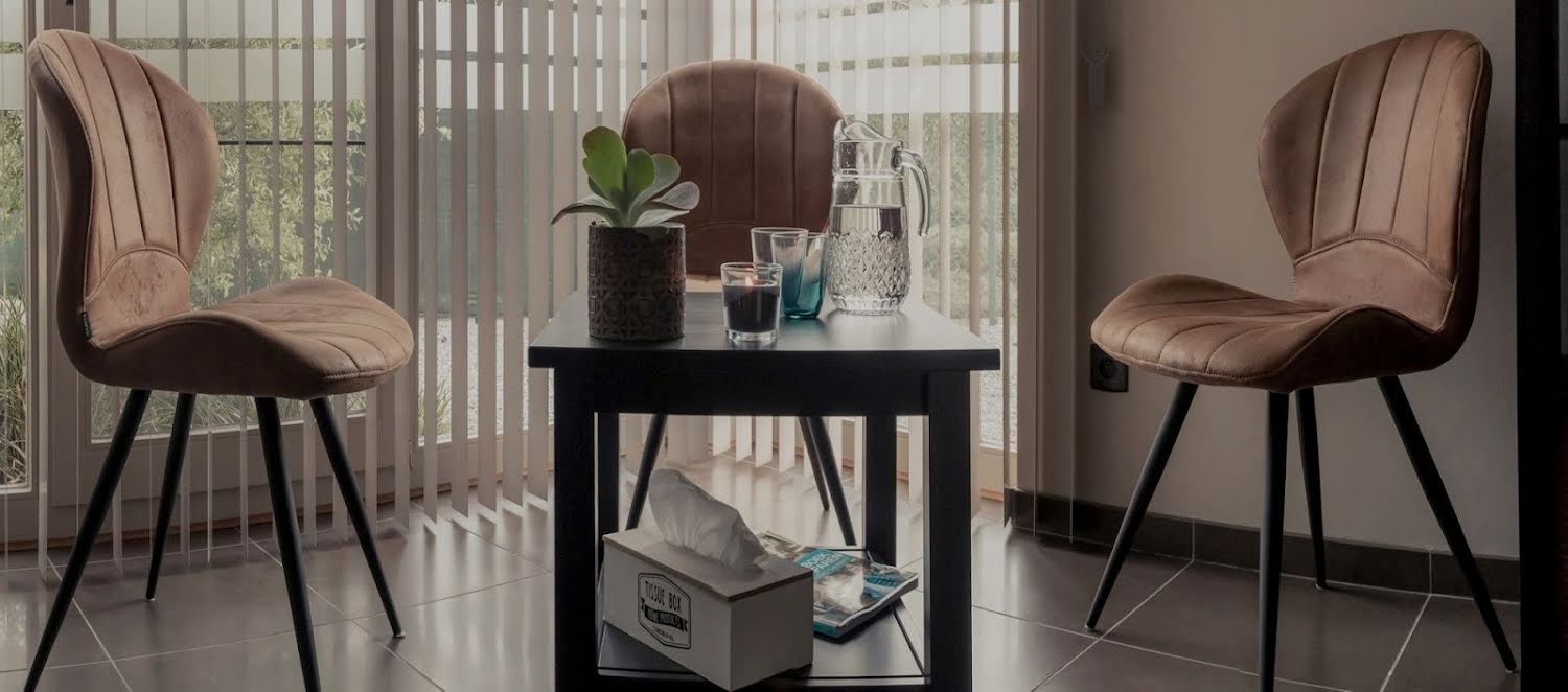 Praktijkruimte met zetels rond een tafeltje met karaf en tissues