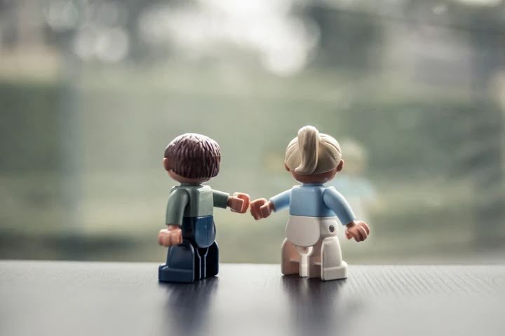 Twee Lego-poppetjes die van achteren gezien een vuistje geven